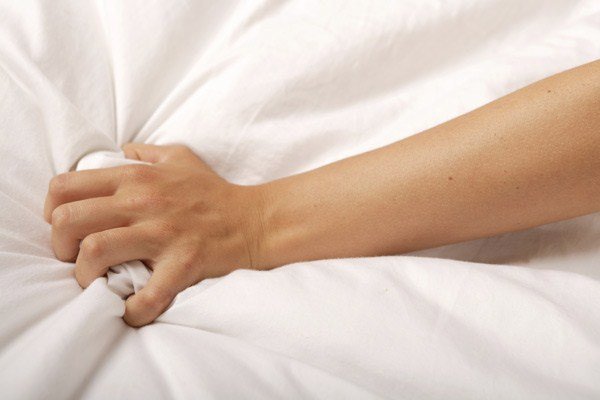 hand clutching bedsheets